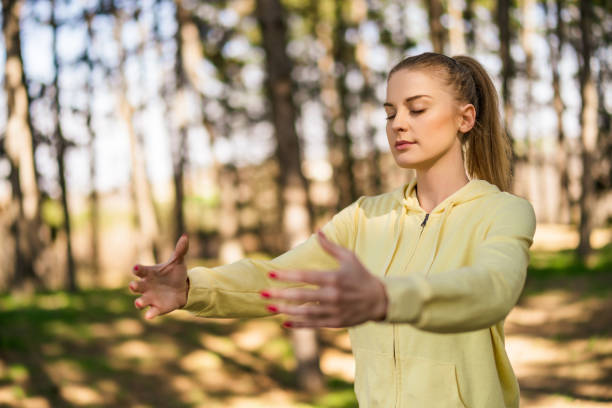 Beautiful Woman Enjoys Exercising Tai Chi In The Nature.